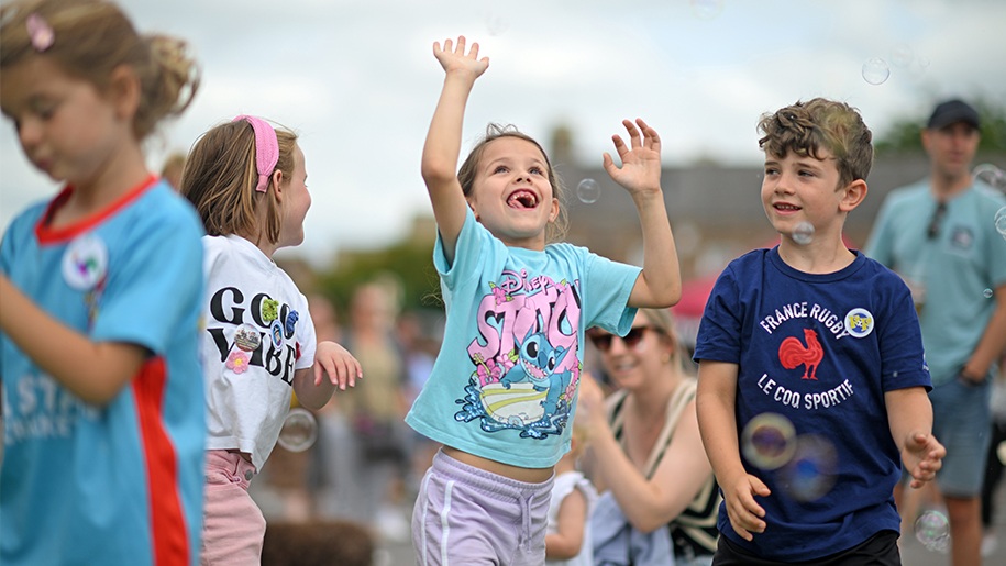 Girl reaching up to burst a bubble.