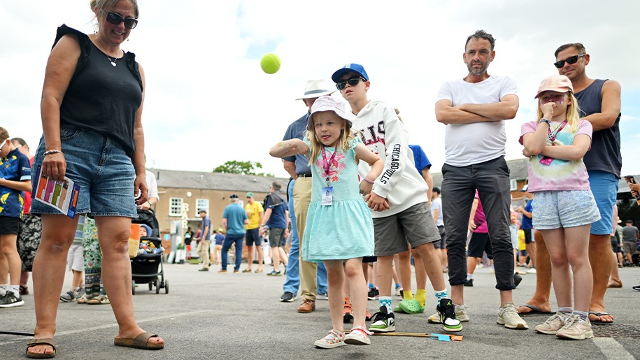 A group of adults and children watching a family sports challenge.