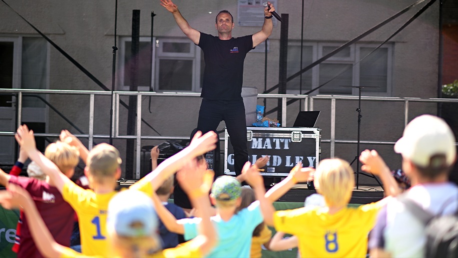 Man with a microphone on a stage entertaining children.