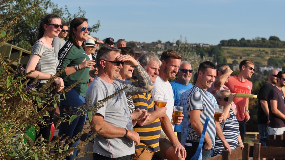 Crowd of adults watching an event in the sunshine.
