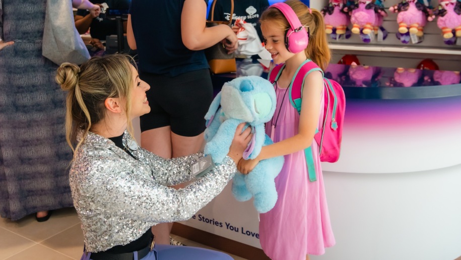 Disney Store assistant giving a soft toy to a little girl.