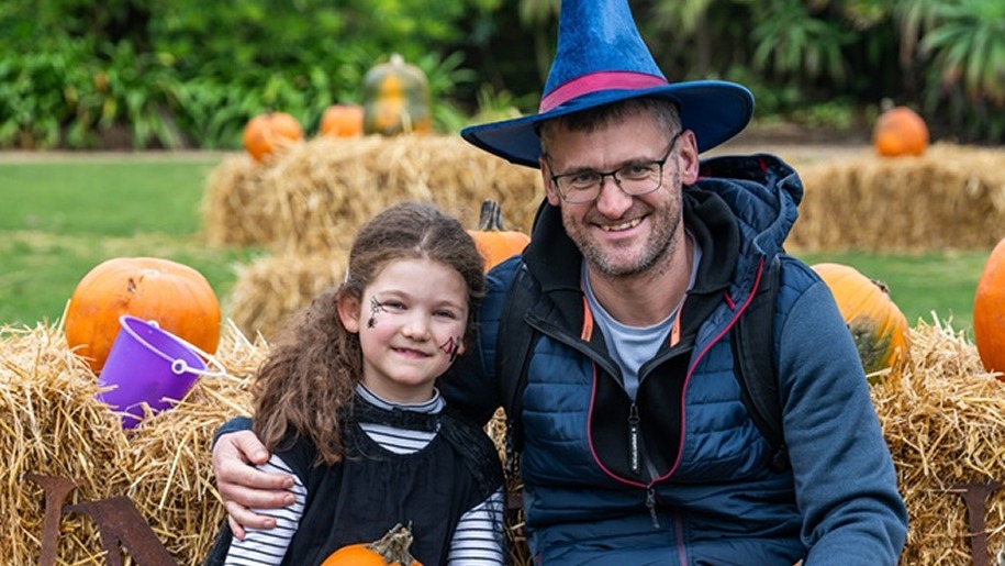 Father and daughter wearing Halloween fancy dress in a pumpkin patch.