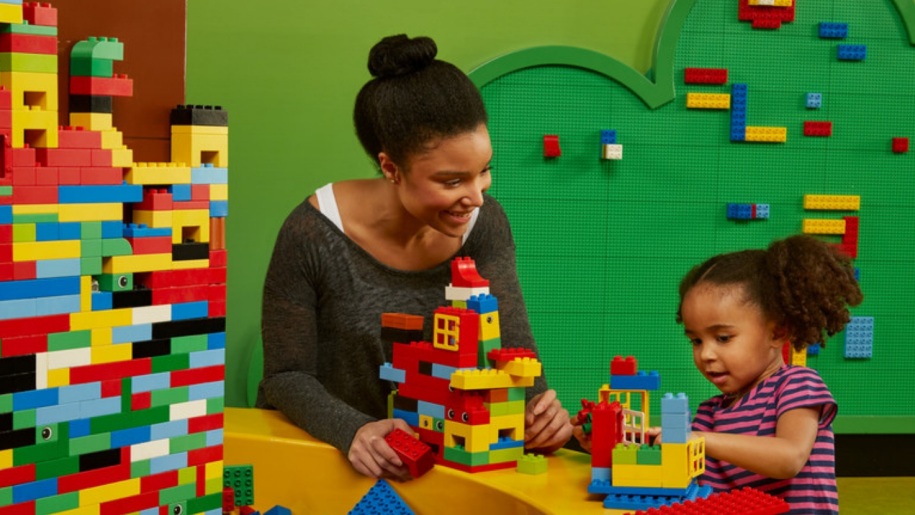 A mother and child building with LEGO bricks.