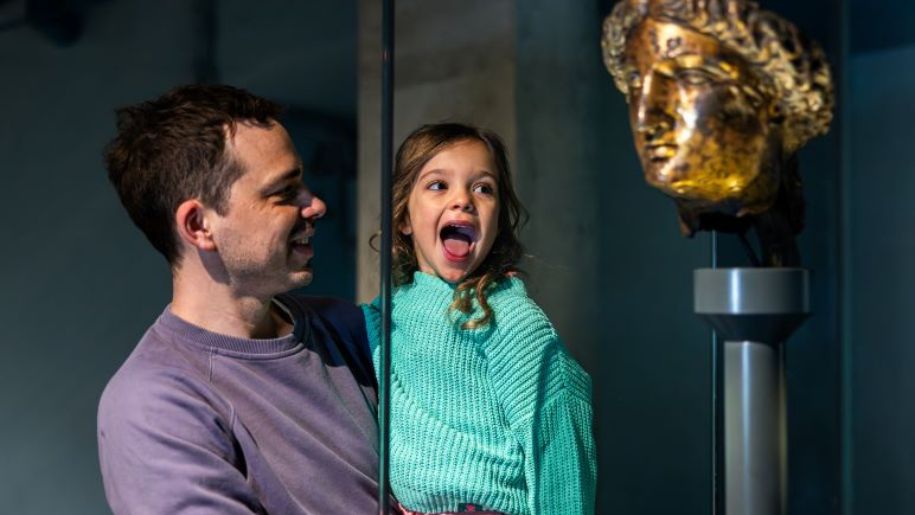 girl and dad look at roman head statue