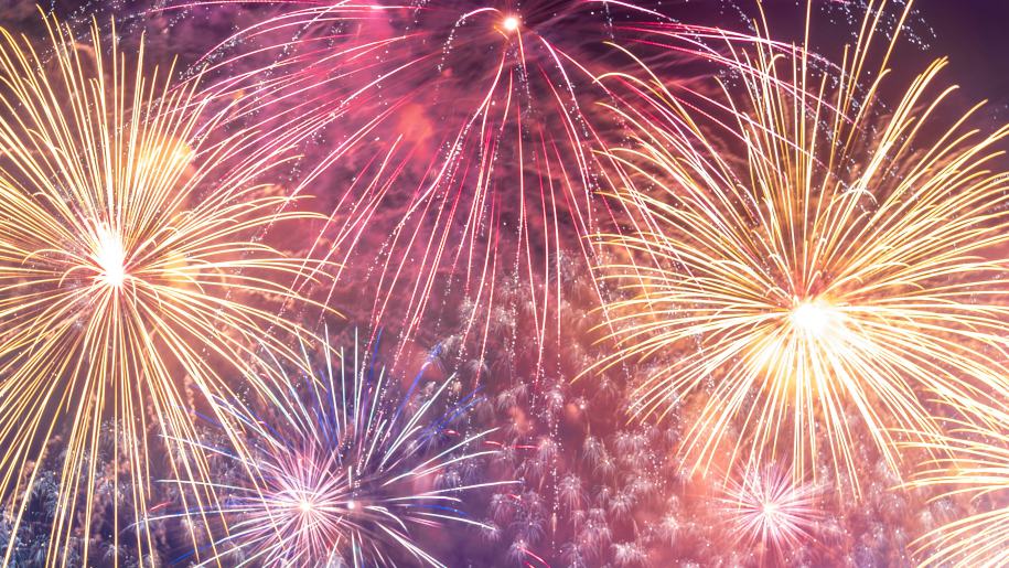 Yellow, pink and purple fireworks lighting up the night sky.