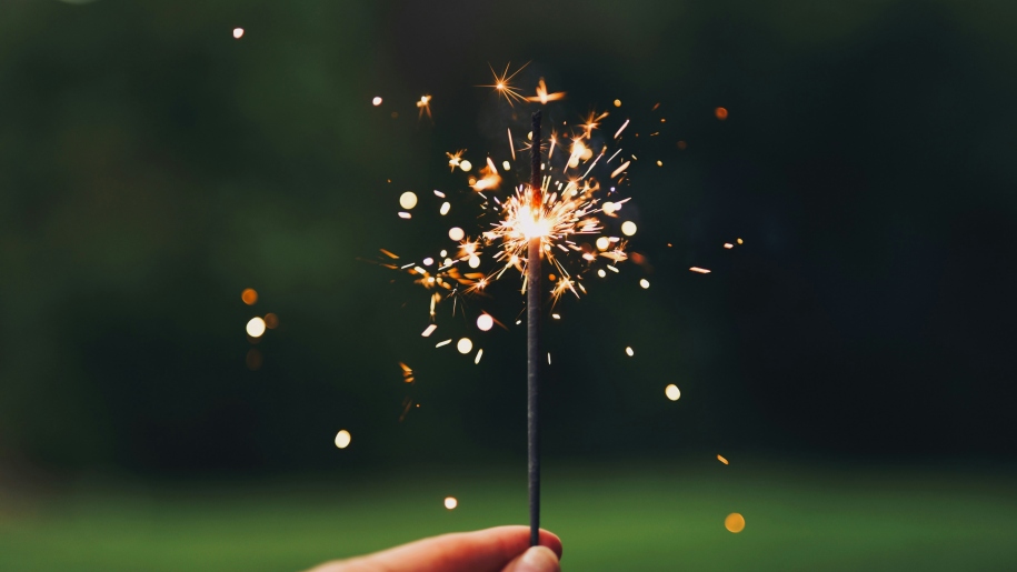 Hand holding a sparkler in the dark.