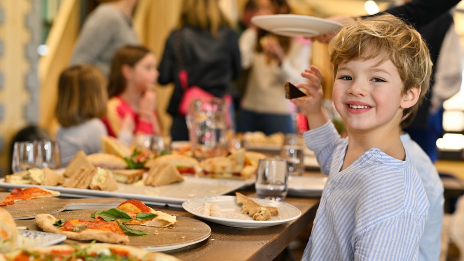 Children around a table of birthday party food.