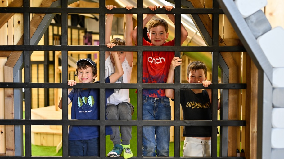 Four boys looking through a metal grill.