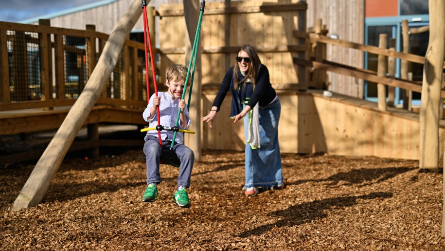 Mother pushing child on a swing.