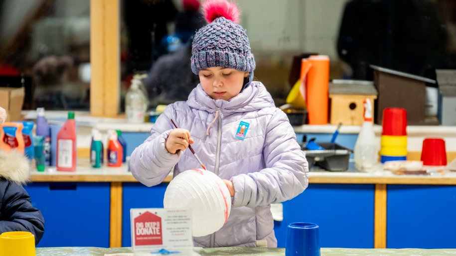 Child painting a lantern at a lantern making workshop.