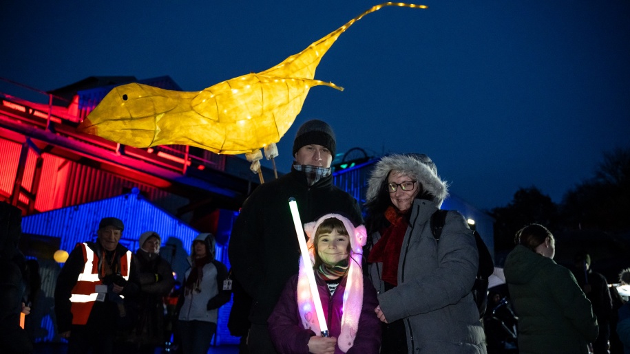 Child holding a lantern in the shape of a big bird.