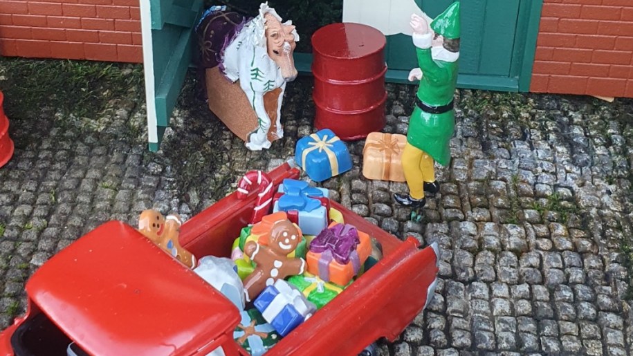 A model Elf loading Christmas presents into a little red truck.