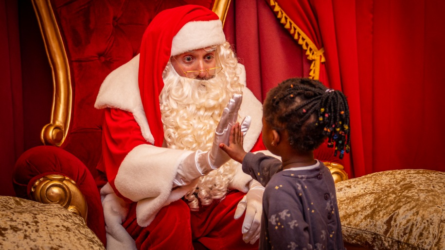 Santa greeting a young visitor in his grotto.