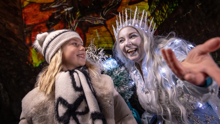 Girl and the Ice Queen outside Edinburgh Castle illuminated for Christmas.