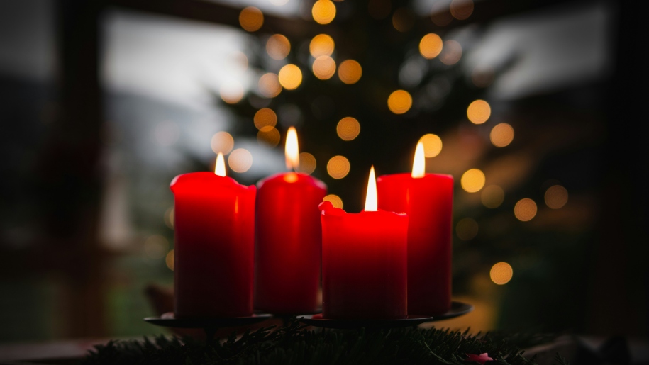 Four red candles with twinkling lights in the background.