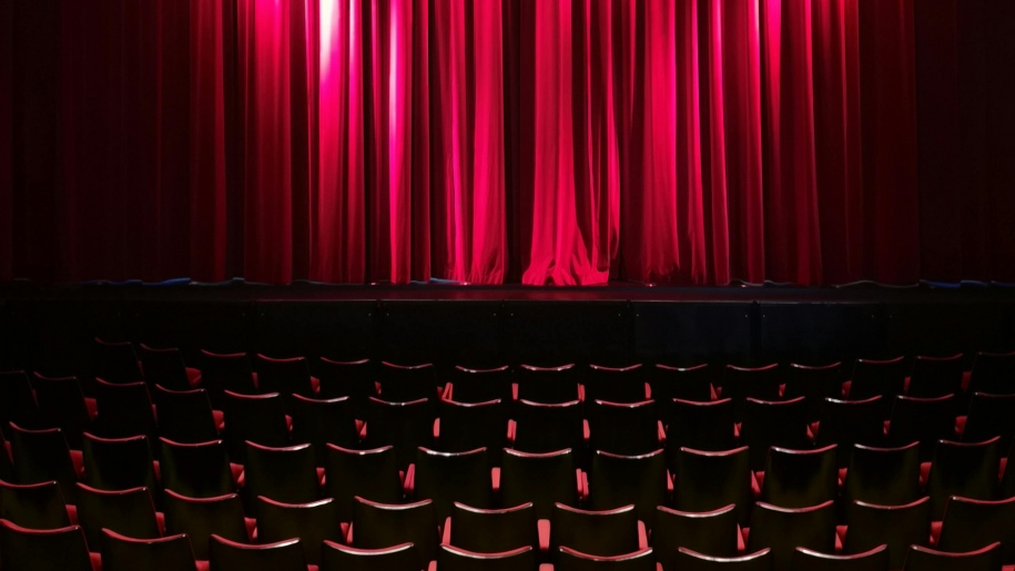 Empty seats, stage and drawn red curtain in a theatre.