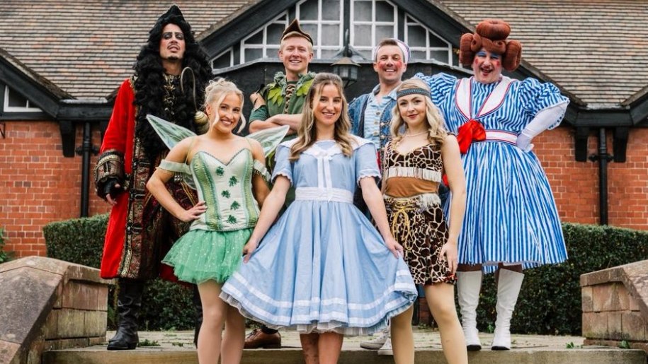 Group of pantomime characters outside a building.