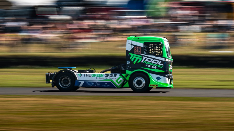 Bright green, black and white truck on a race circuit.