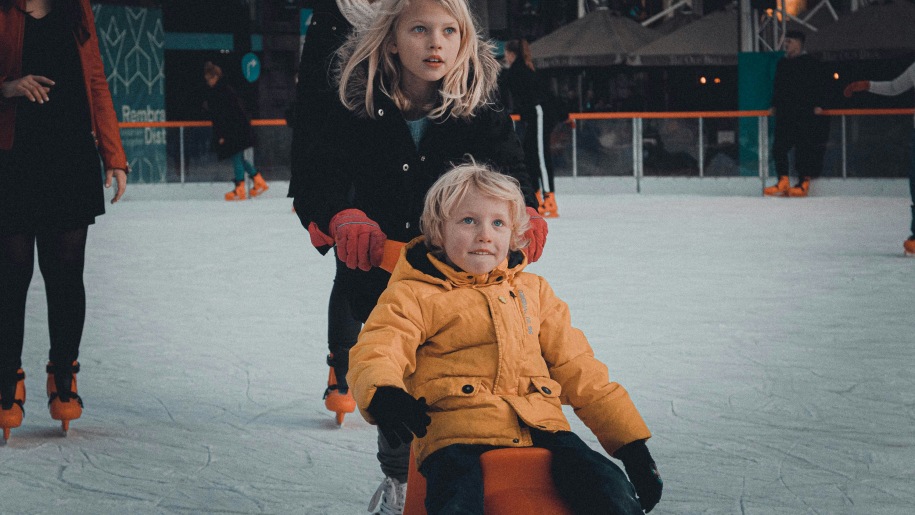 Children using a skate aid at an ice rink.