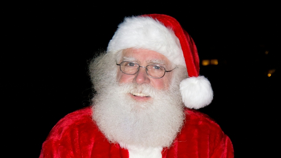 Man dressed as Santa in red and white coat and hat.