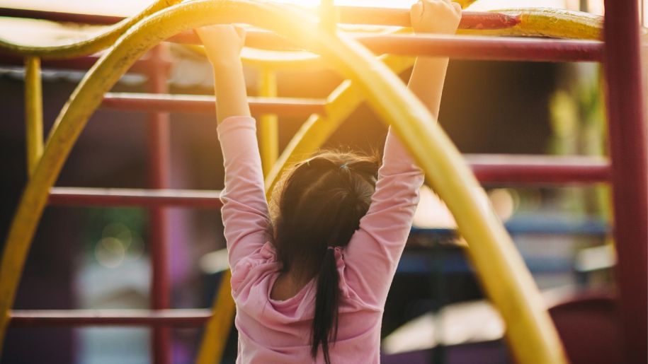 girl hangs on climbing frame