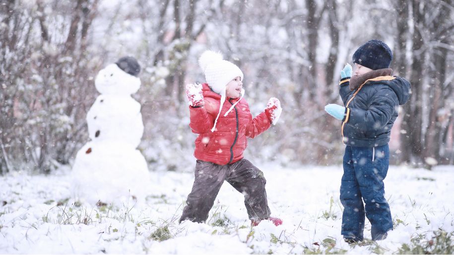kids playing iin the snow with a snowman