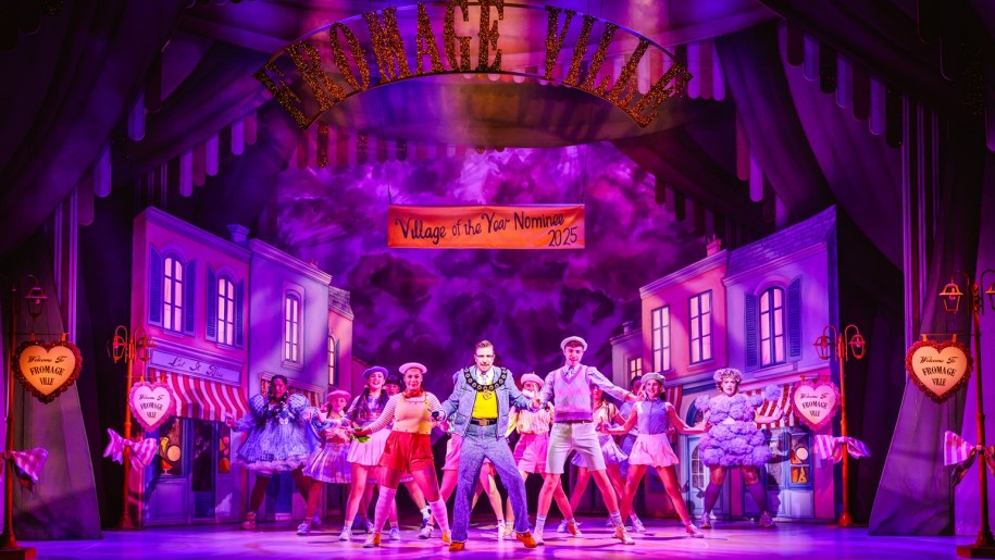 Cast of a Christmas show dancing on a stage.