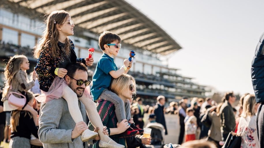 Children sitting on parents' shoulders at Ascot Racecourse.