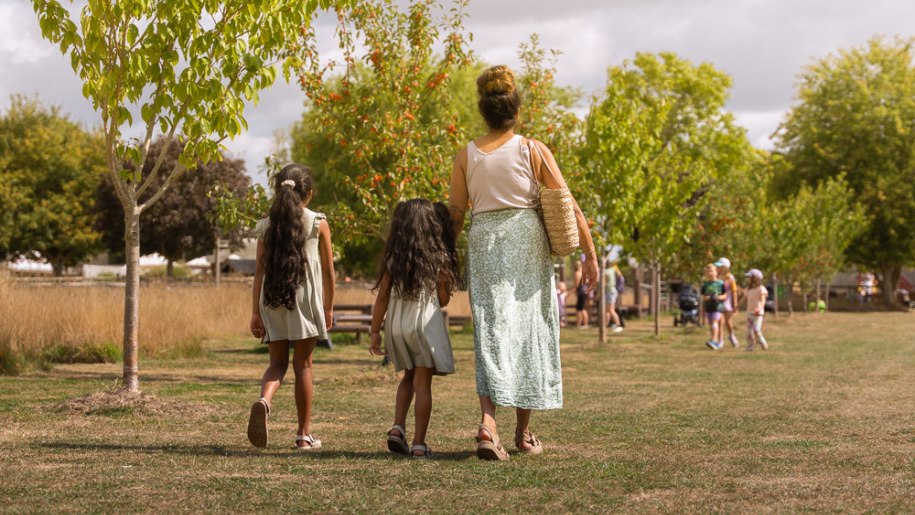 Mother and her two children walking on grass.