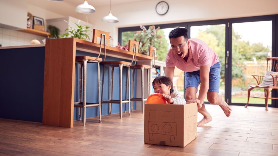 man pushing son in a cardboard box drawn on car