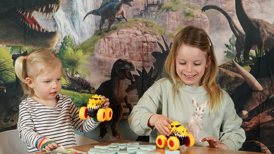 two blonde girls play with diggers