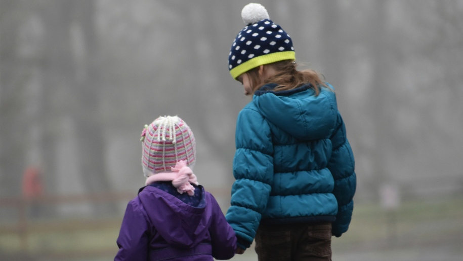 Two children in outdoor clothing walking in winter.