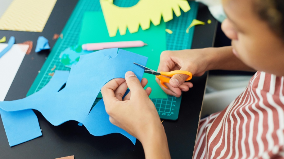 A child using scissors to cut craft paper.