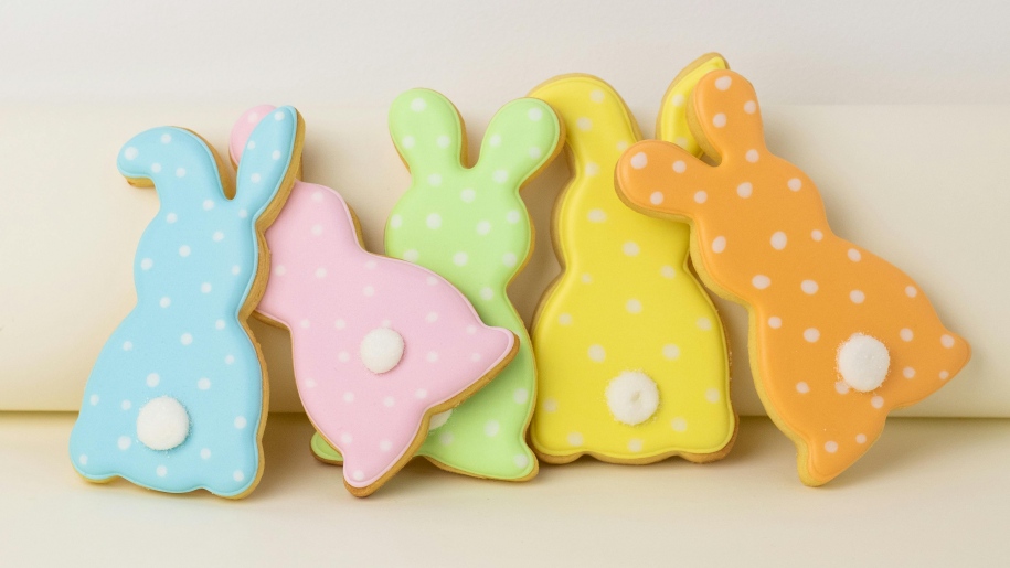 Five Easter bunny shaped cookies iced in pastel colours.