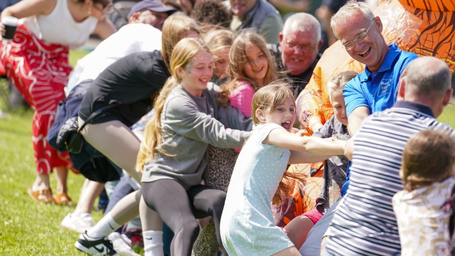 Children and adults taking part in a tug of war.