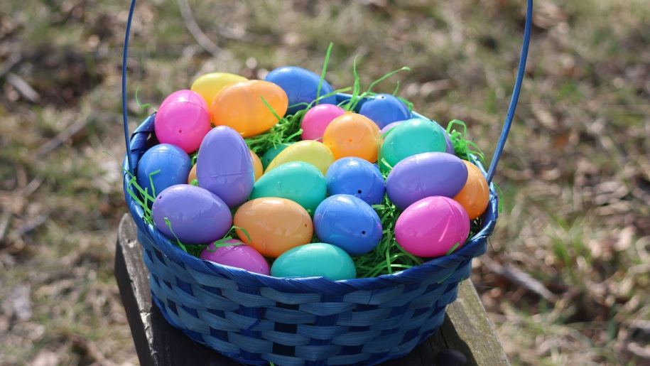 Blue wicker basket full of brightly coloured plastic Easter eggs.