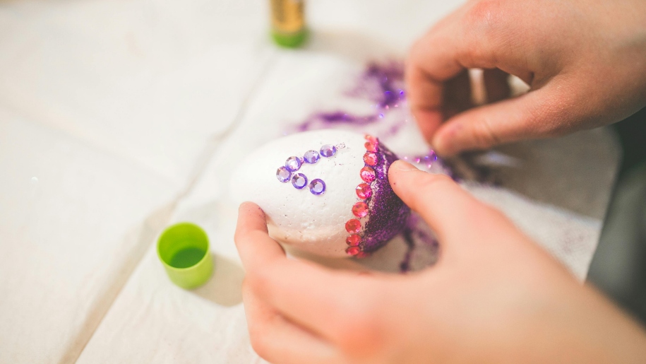 Hands decorating an Easter egg.