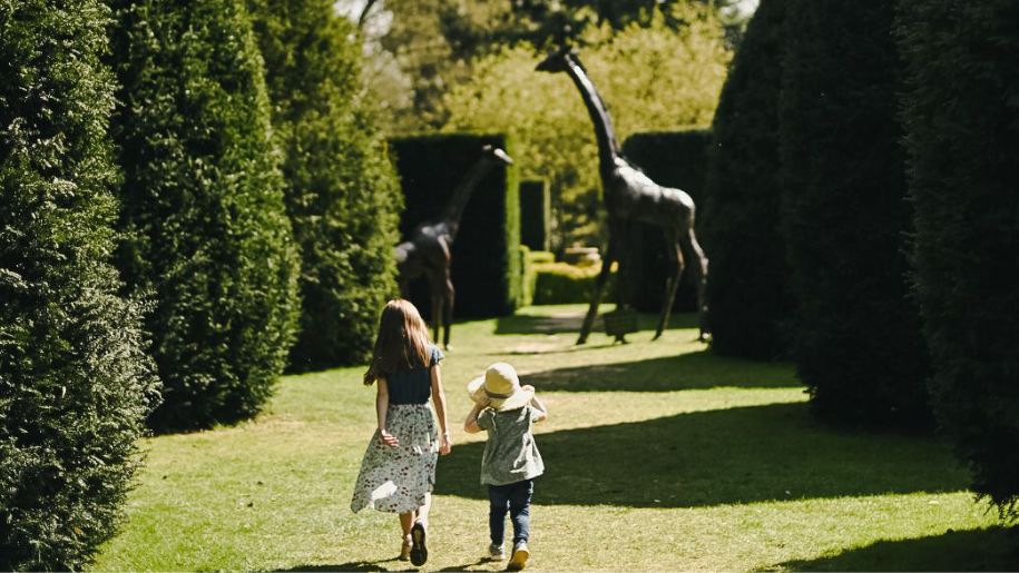 two children walk through sunshine gardens