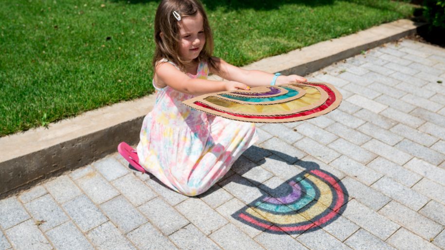 girl holds diy sun catcher over patio in sunny garden