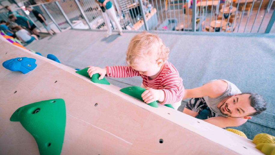 toddler climbing a rock climbing wall