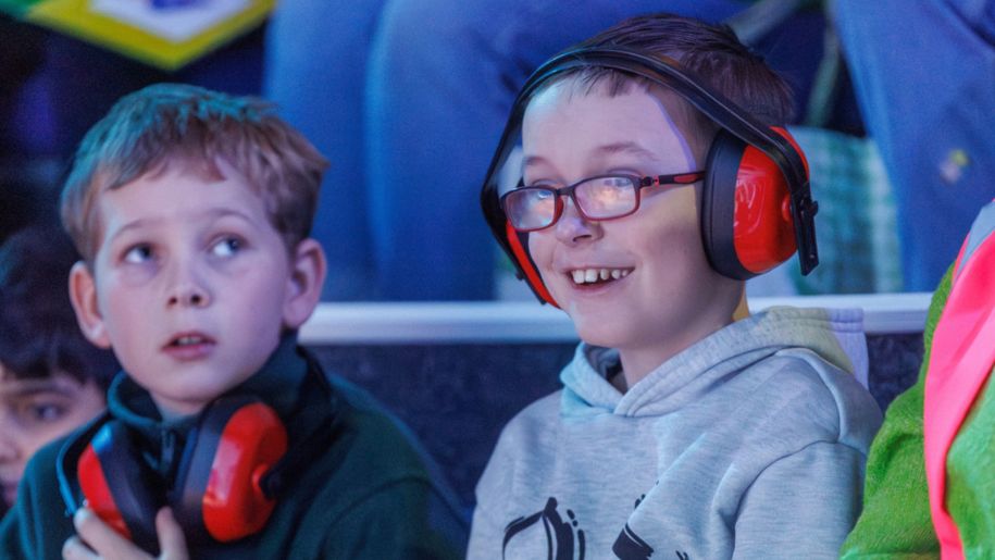 two boys in a darkened room with red headphones on