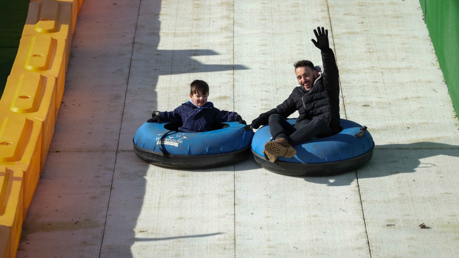 Boy and man sliding down a wooden slide on inflatable ringos.