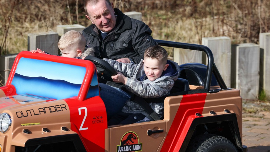 Boy driving a small jeep with two passengers.