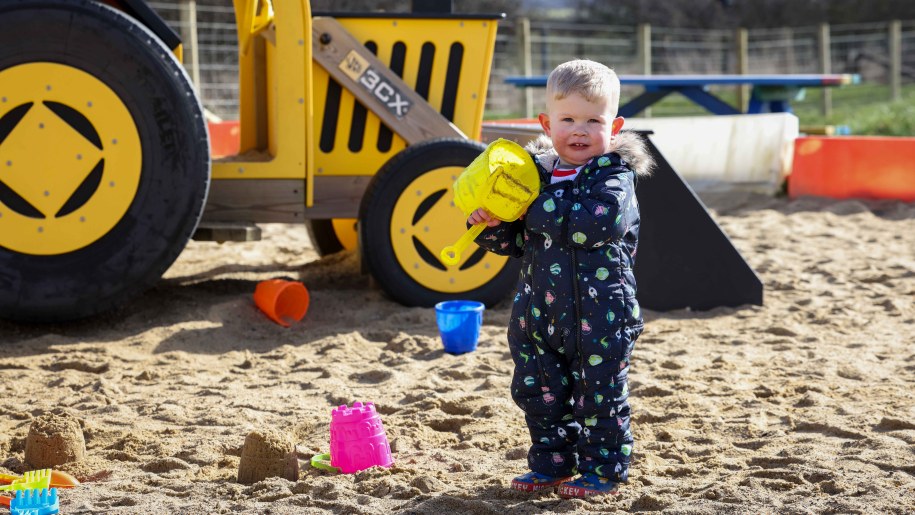 Young child with bucket and spade in a sand pit.