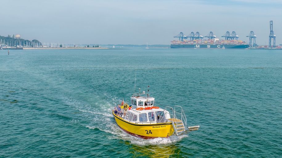 yellow boat on marina water with port behind it