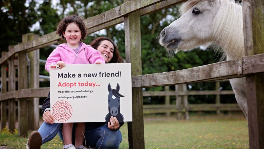 girl holds an adoption sign next to a horse