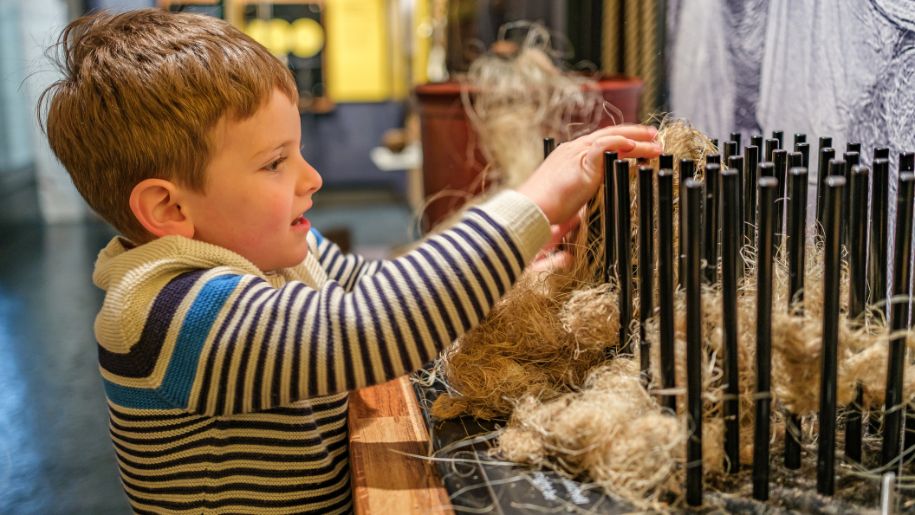 boy plays with the rope exhibits around metal poles