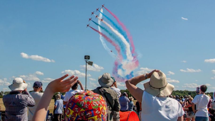 planes in formation in blue sky with crowd under