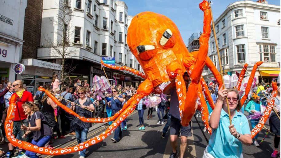 Huge orange model of an octopus being carried in a street parade.