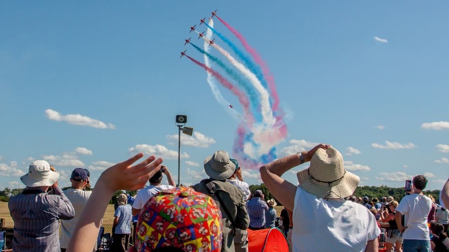 Crowd watching a flying display with coloured vapour trails at Shuttleworth.